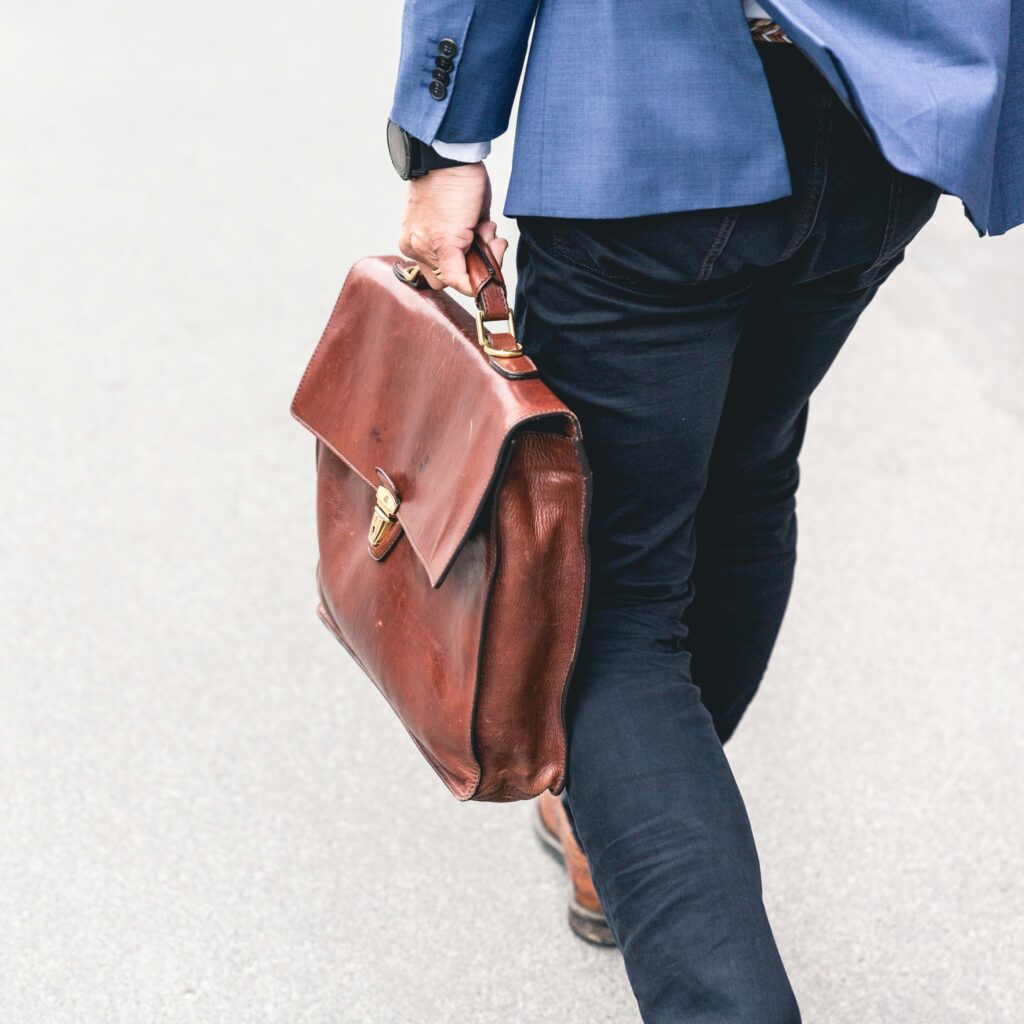 Man walking with leather briefcase in hand, seen from the back, close up
