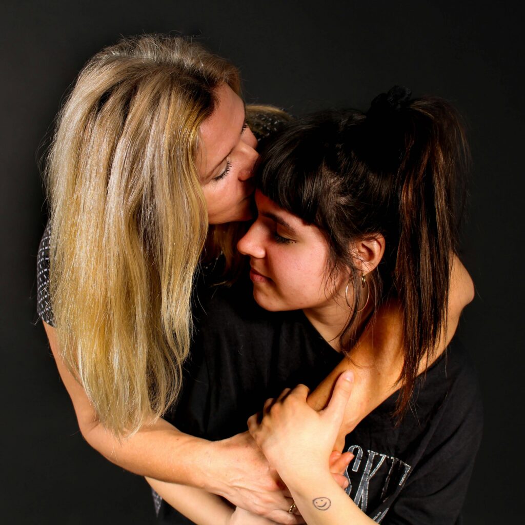 Mother hugging teen-aged daughter. Daughter smiling.