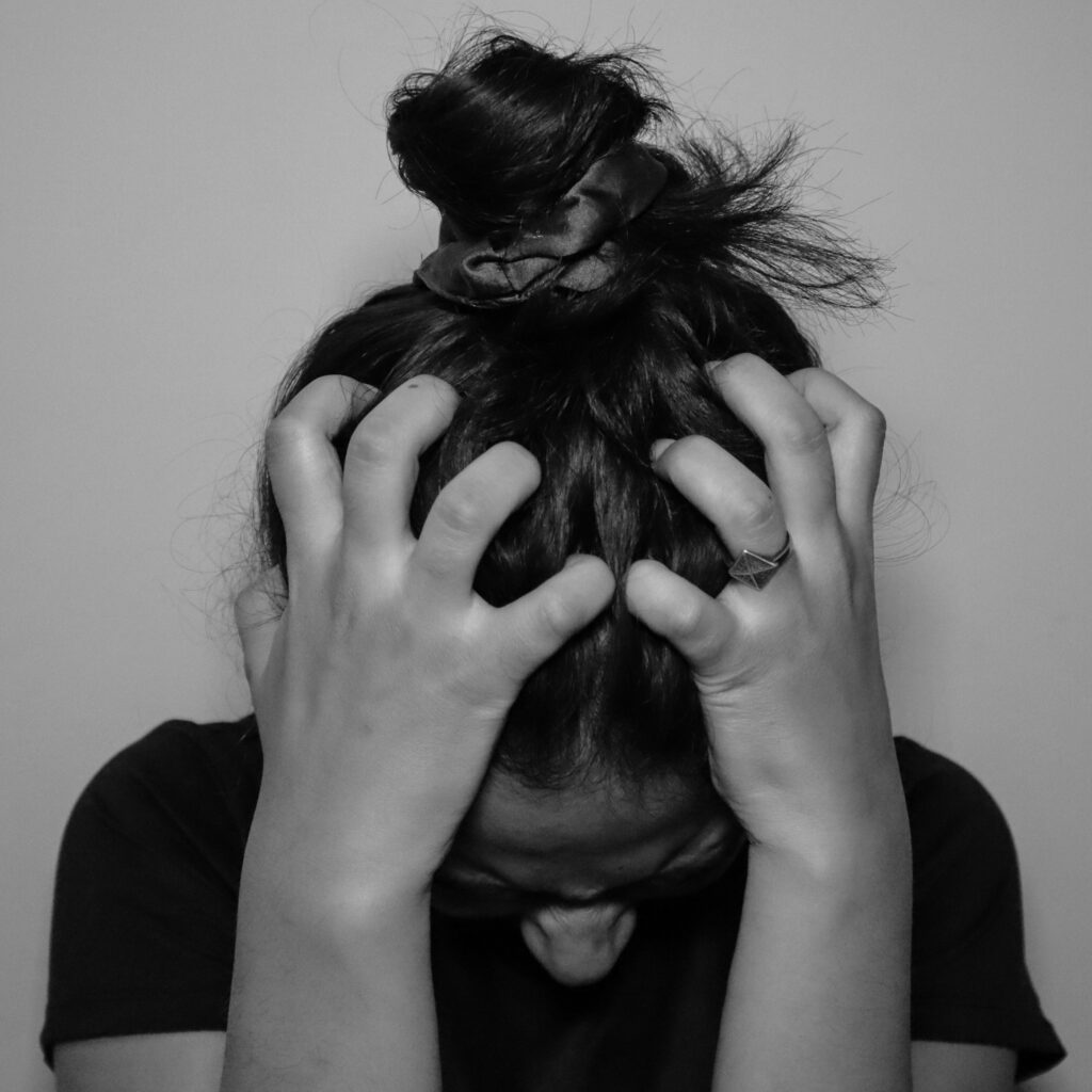 black and white image of a girl holding her head in frustration